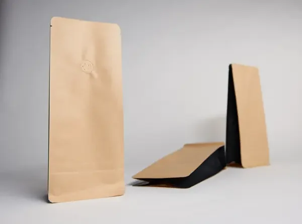 Kaffeebeutel Braune und schwarze Papierverpackungen in verschiedenen Positionen auf hellem Hintergrund.